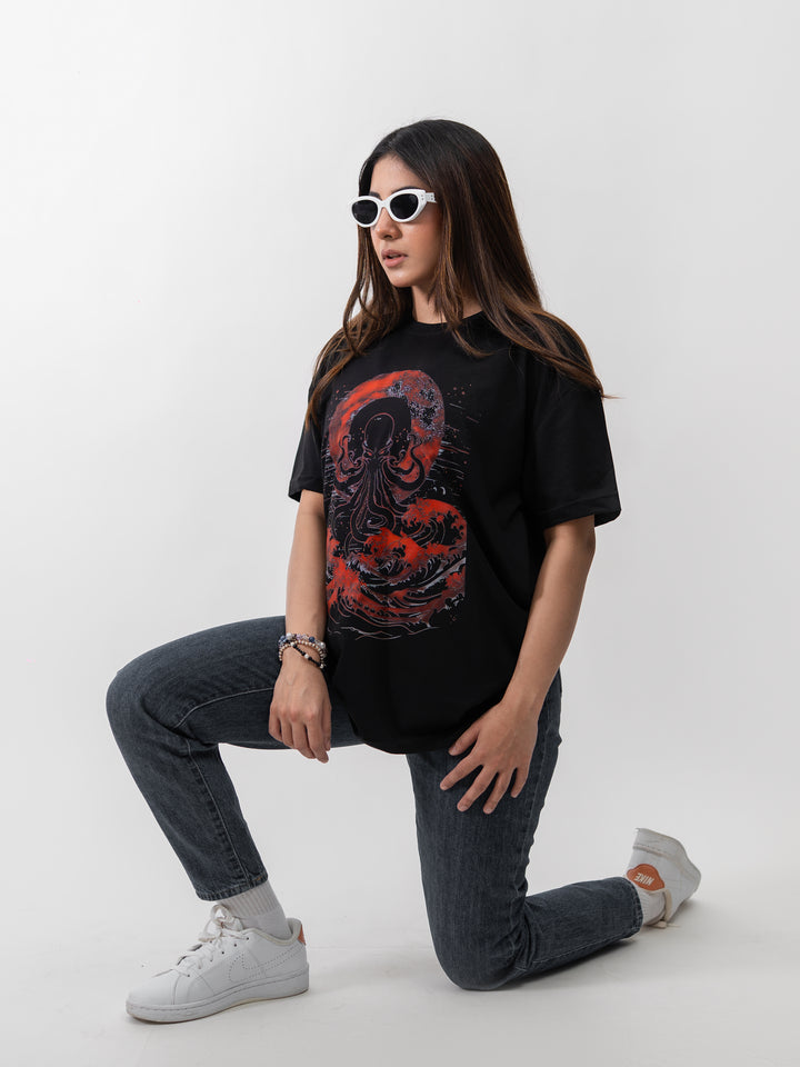 Woman wearing black oversized Kraken graphic drop-shoulder T-shirt by Herculean Knight, front view.