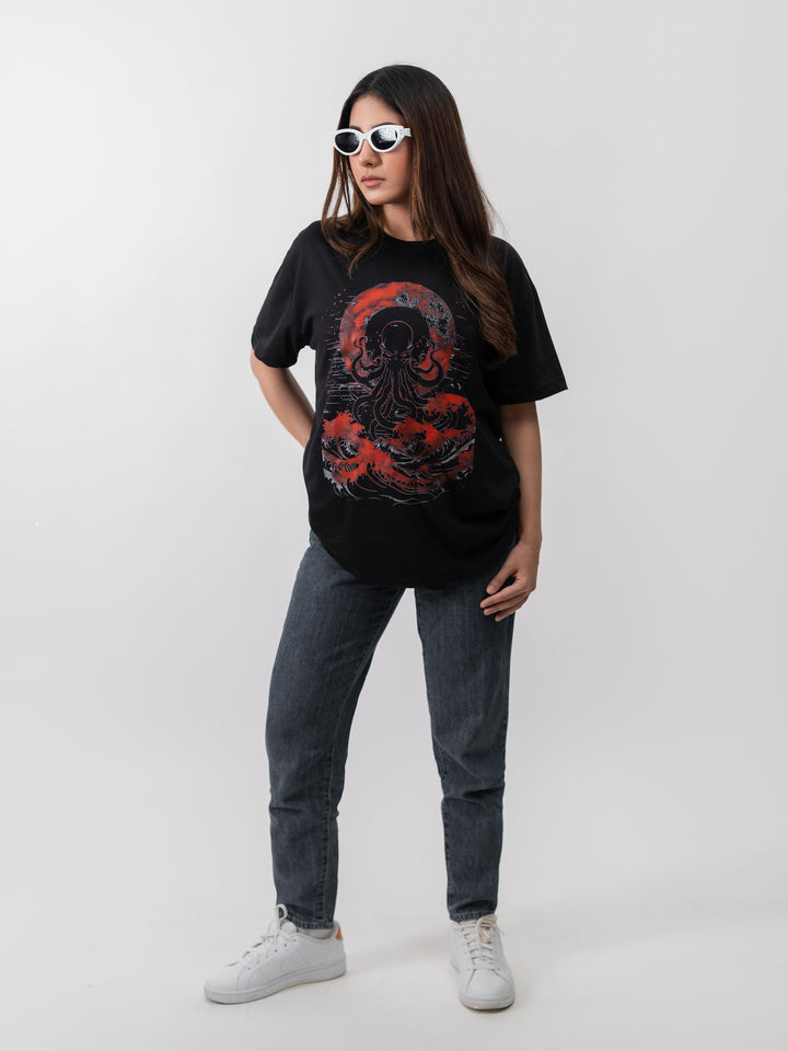Woman wearing black oversized Kraken graphic drop-shoulder T-shirt by Herculean Knight, front view.